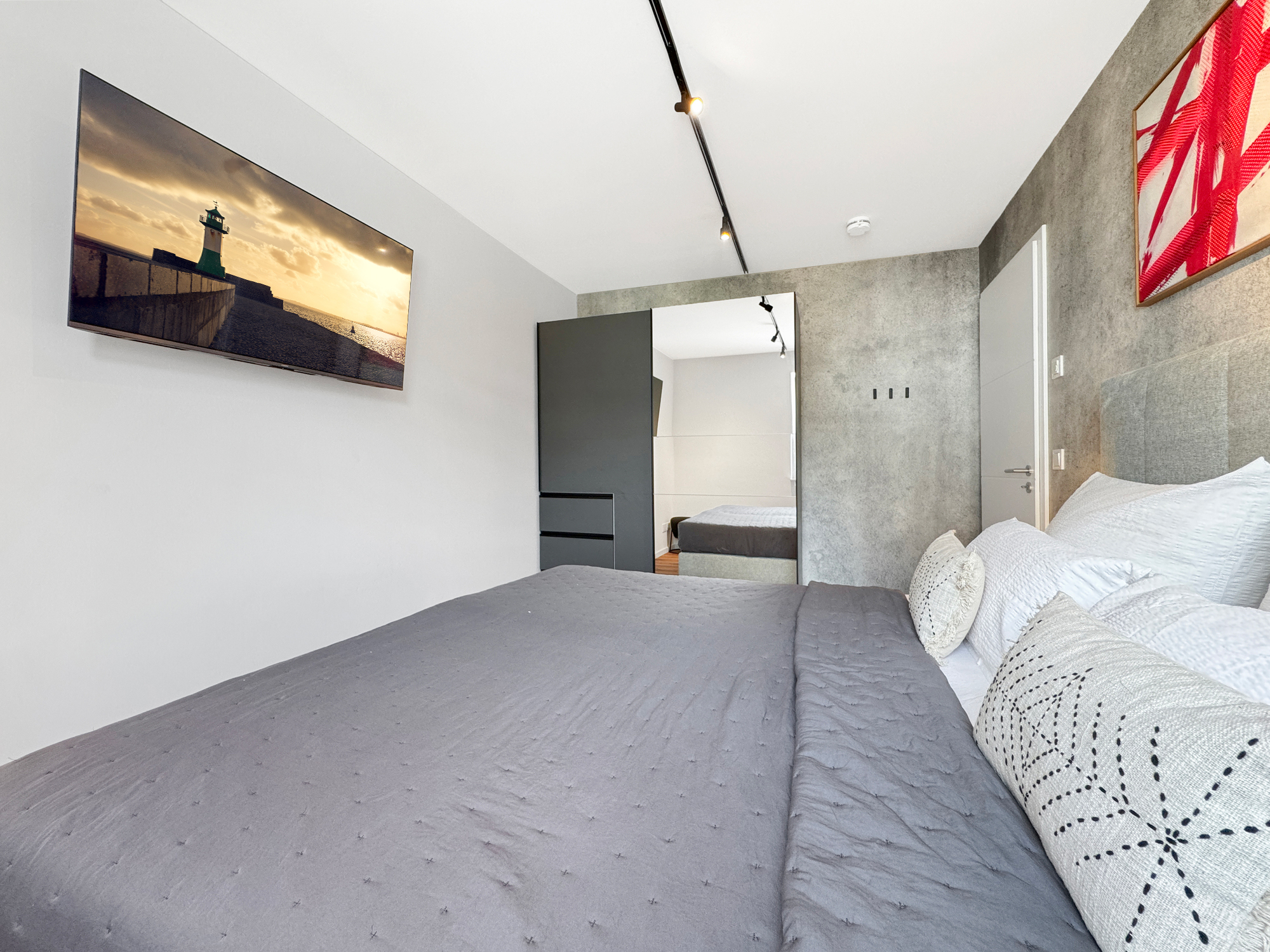 Schlafzimmer mit großem Smart-TV und Schwebetürenkleiderschrank