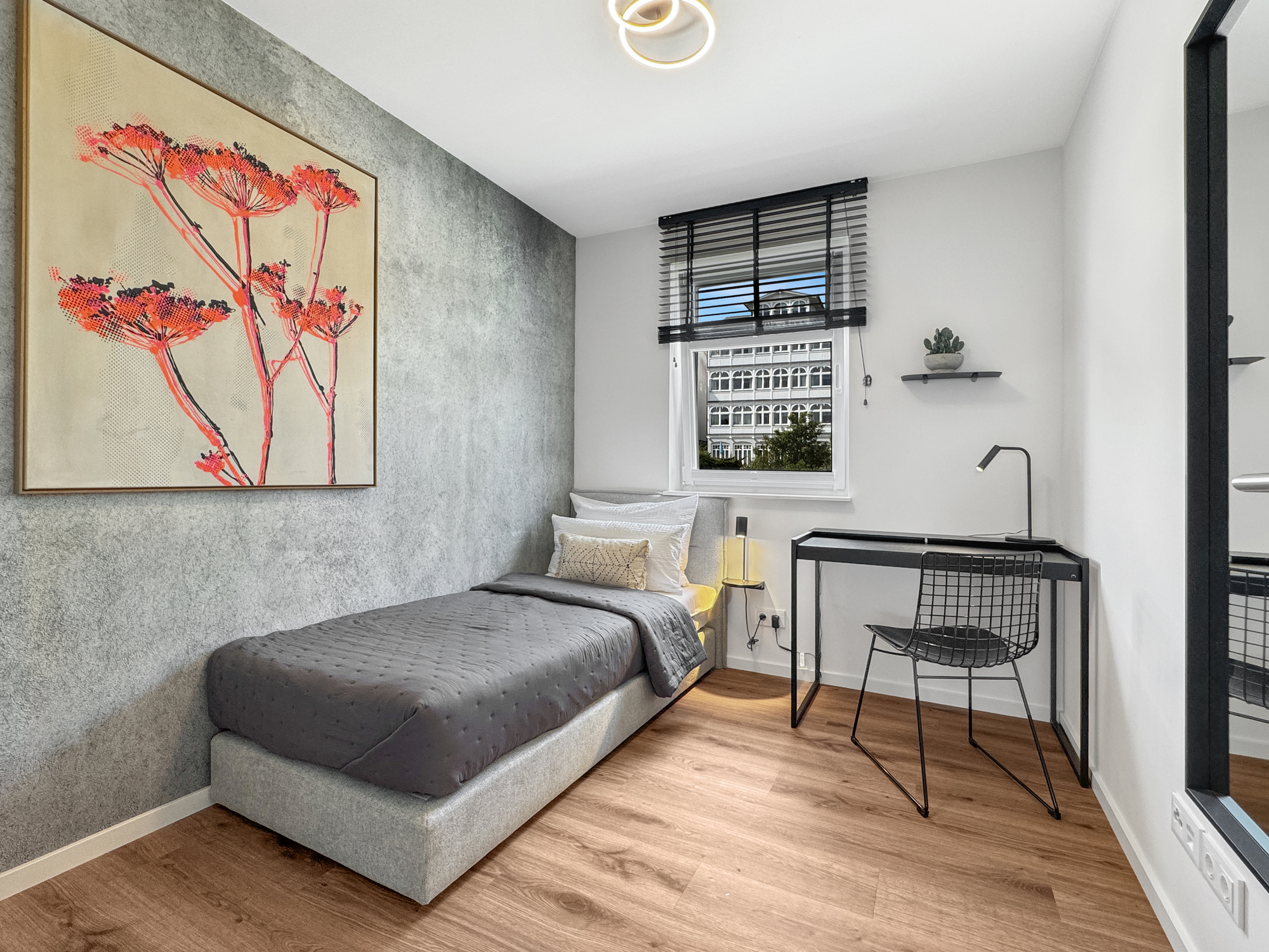 Zweitschlafzimmer einer löffelfertig eingerichteten Ferienwohnung mit individueller Wandkunst, Boxspringbett und Arbeitsplatz