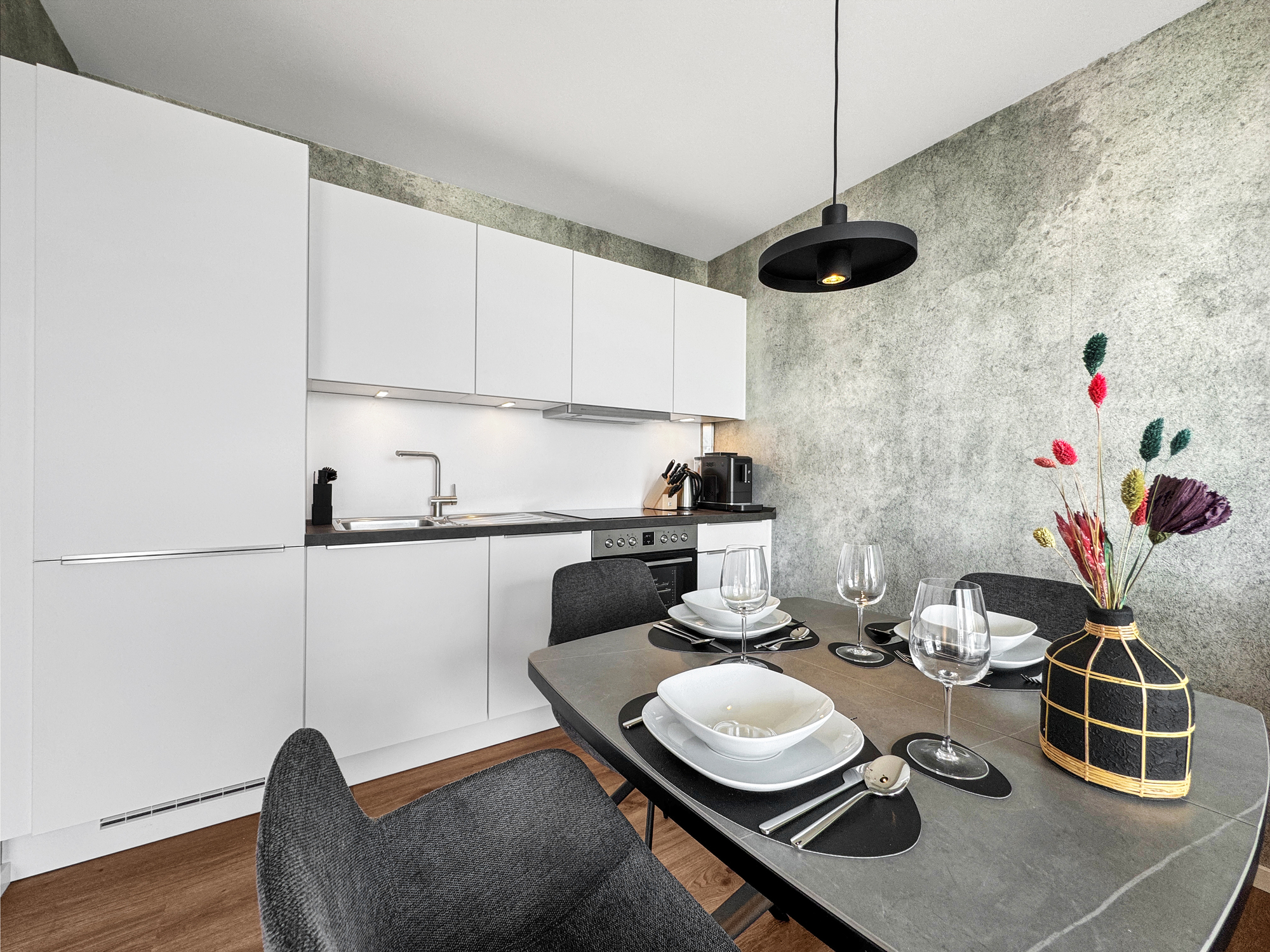 Moderne Einbauküche und Essplatz für drei Personen sowie Tapeten in Sichtbeton-Optik